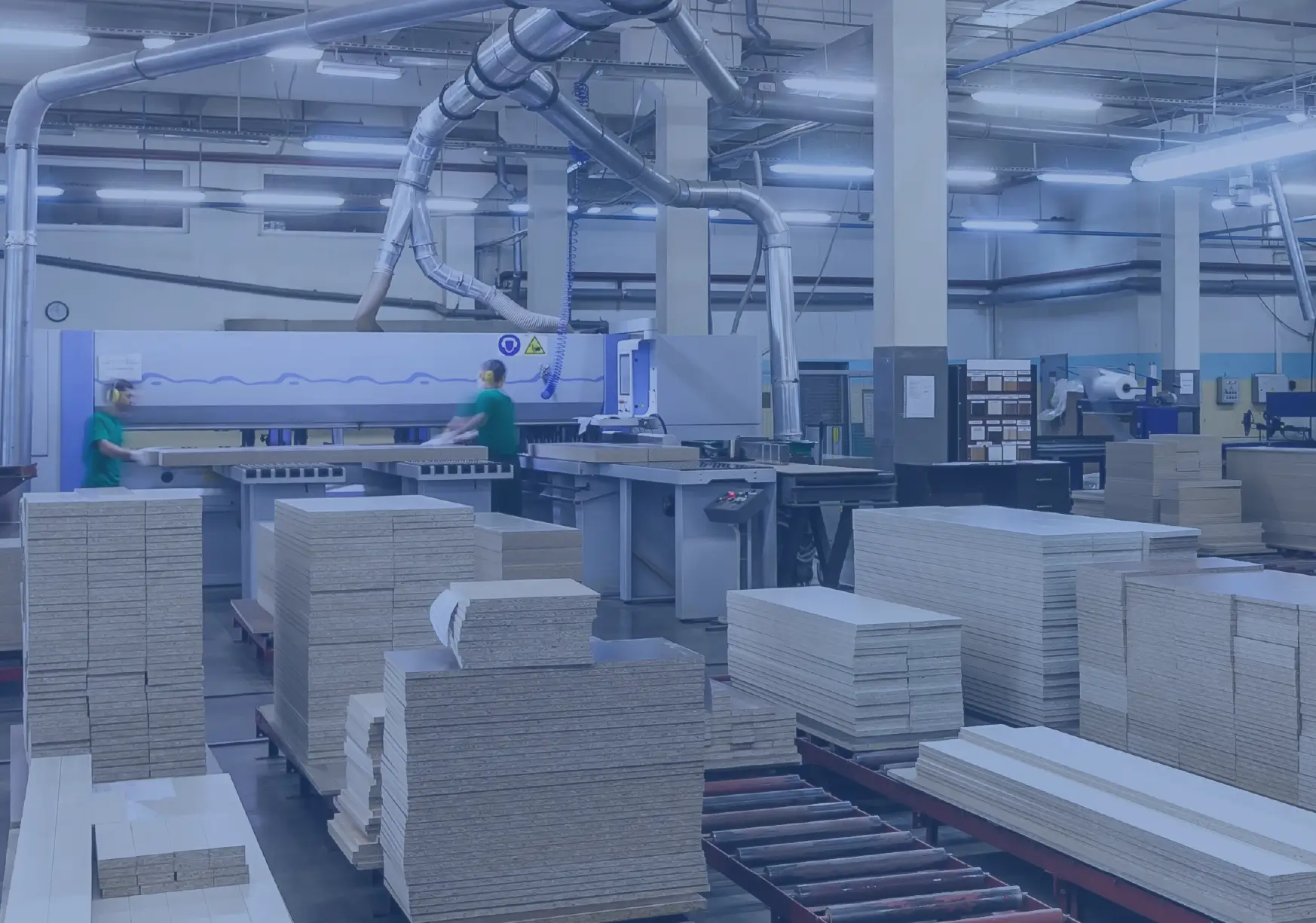 2 workers operating CNC machine with stacks of cabinet panels ready for assembly.
